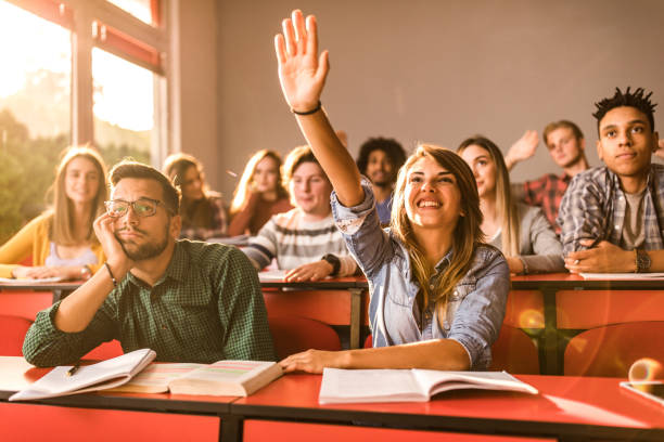 istock Happy female student raising her hand on a class at lecture hall. 1175175202
