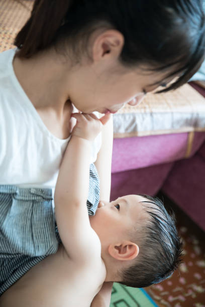 Asian mother breastfeeding and hugging her baby.