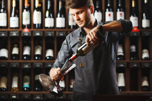 istock Bartender pours red wine in transparent vessel in cellar 1175180448