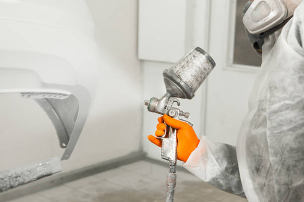 istock Male worker painting a car in a white paint booth. 1175183036