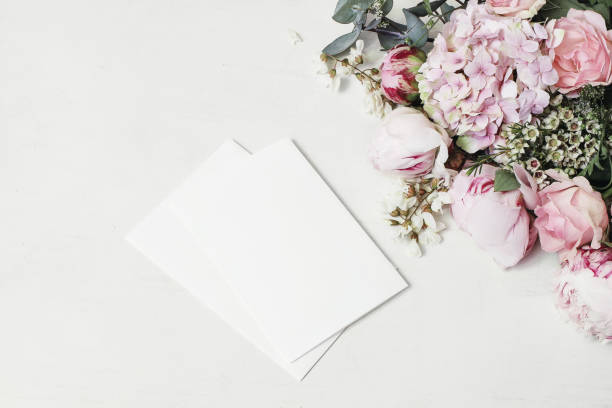 boda femenina, escena de maqueta de cumpleaños. esquina floral decorativa de peonía, hortensia, rosas y flores de langosta. tarjetas de felicitación de papel en blanco sobre fondo de mesa de madera blanca. la grasa estaba, vista superior - beautiful red pink wood fotografías e imágenes de stock