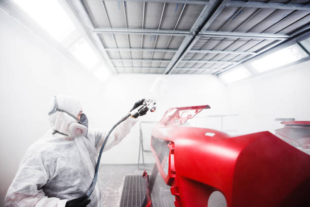 istock Car painter sprays varnish in paint booth. 1175185521