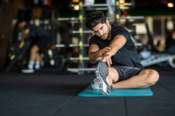 istock Young man doing leg stretches in the gym 1175185635
