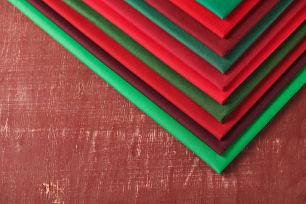 Stack of red and green fabrics on brown background, space for text
