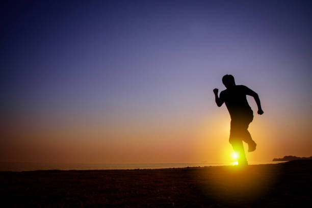 istock Silhouette of Man running on the beach at sunset 1175187545