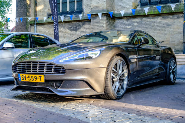 Aston Martin Vanquish sports car parked in a square in the city of Zwolle during a sunny summer morning. People in the background are looking at the cars.