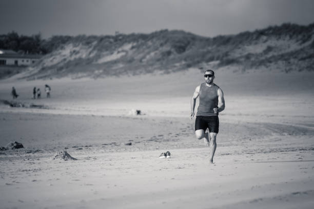 Athlete runner running barefoot on beach at sunset. Sport man fitness model working out on sea shore in outdoors fitness training, sports, motivation and active healthy lifestyle concept. corredor atleta corriendo descalzo en la playa al atardecer. modelo de fitness del hombre deportivo haciendo ejercicio en la orilla del mar en entrenamiento de fitness al aire libre, deportes, motivación y concepto de estilo de vida saludable activo.