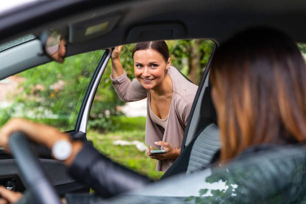 Ridesharing A woman is getting into a car and is looking at the driver. car pooling stock pictures, royalty-free photos & images