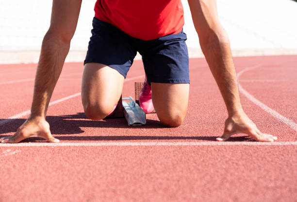 istock Runner using starting block to start his run on race track. Runner using starting block to start his run on running track in a stadium. Athlete starting his sprint on an all-weather running track. 1175197177