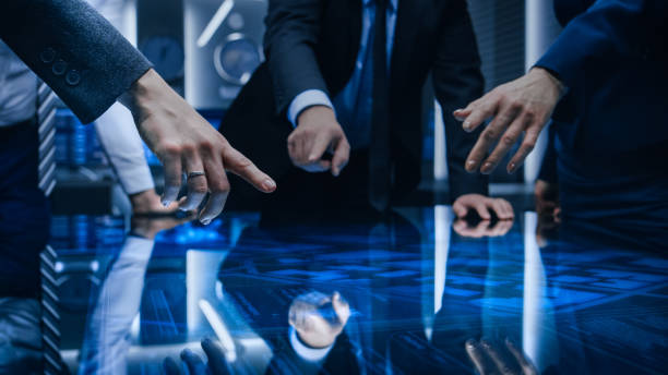 istock Diverse Team of Government Intelligence Agents Standing Around Digital Touch Screen Table and Satellite Tracking Suspect, Pointing at Display. Big Dark Surveillance Room. 1175197195