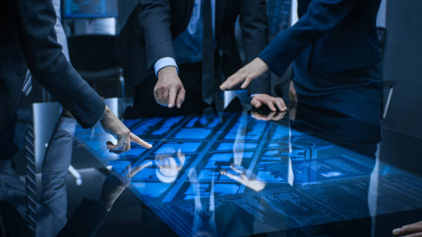 istock Diverse Team of Government Intelligence Agents Standing Around Digital Touch Screen Table and Satellite Tracking Suspect, Pointing at Display. Big Dark Surveillance Room. 1175197231