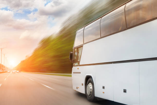 Big luxury comfortable tourist bus driving through highway on bright sunny day. Blurred motion road. Travel and coach tourism concept. Trip and journey by vehicle