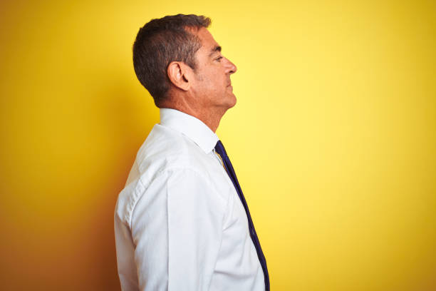 istock Handsome middle age businessman standing over isolated yellow background looking to side, relax profile pose with natural face with confident smile. 1175202122