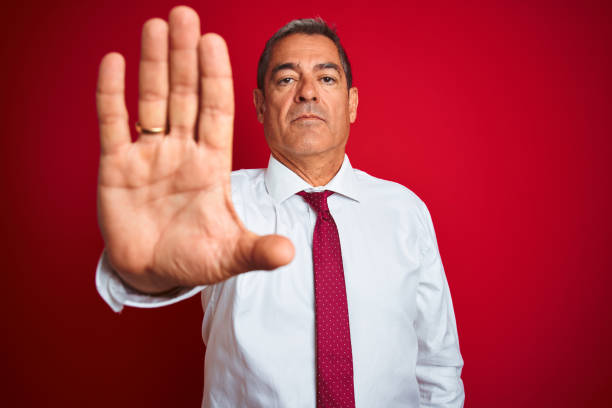 istock Handsome middle age businessman standing over isolated red background doing stop sing with palm of the hand. Warning expression with negative and serious gesture on the face. 1175203194