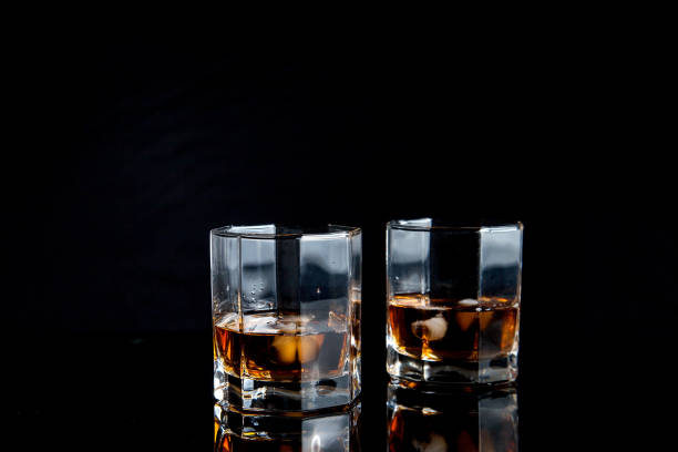 istock Two glasses of whiskey with ice isolated on black background. 1175203862