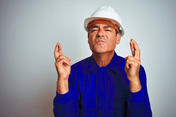 istock Handsome middle age worker man wearing uniform and helmet over isolated white background with sad expression covering face with hands while crying. Depression concept. 1175204410