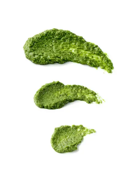 Pesto spread or blob isolated on white background. Green italian homemade spilled sauce made of ground basil, garlic, pine seeds, olives and pecorino sardo cheese top view