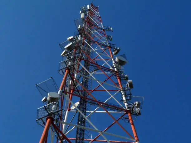 broadcasting, cell transmitter and receiver tower. symbolizing modern way of messaging and communication. tv signal receiving antenna. blue sky background. steel truss tower with service platforms.