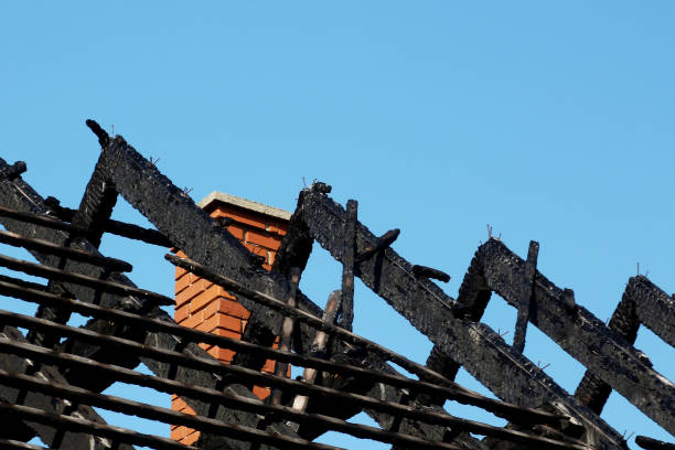 exposed charred burnt black timber roof structure after fire damage. abstract view of rafters under blue sky. fire safety and insurance concept. fire hazard, fammable materials in construction.