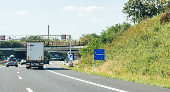 Netherlands - Aug 22, 2019: Truck driving past the Nederland sign at the border between Germany and Netherlands with text on the road sign with European union stars