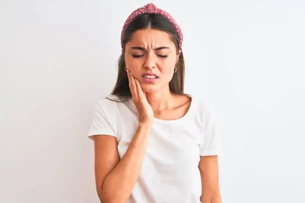 Young beautiful woman wearing casual t-shirt and diadem over isolated white background touching mouth with hand with painful expression because of toothache or dental illness on teeth. Dentist concept.