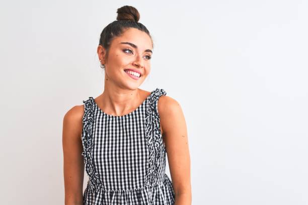 Beautiful woman with bun wearing casual dresss standing over isolated white background looking away to side with smile on face, natural expression. Laughing confident. Beautiful woman with bun wearing casual dresss standing over isolated white background looking away to side with smile on face, natural expression. Laughing confident. hair bun stock pictures, royalty-free photos & images