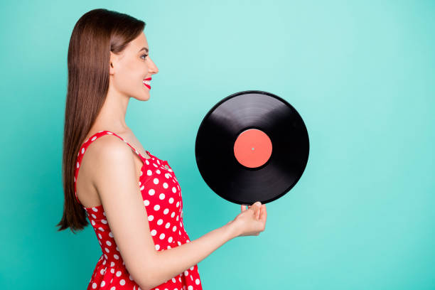 photo d'accompagnement de profil de belle fille retenant le disque de gramophone utilisant la jupe de robe de point de polka d'isolement au-dessus du fond turquoise de sarcelle - polka dot audio photos et images de collection