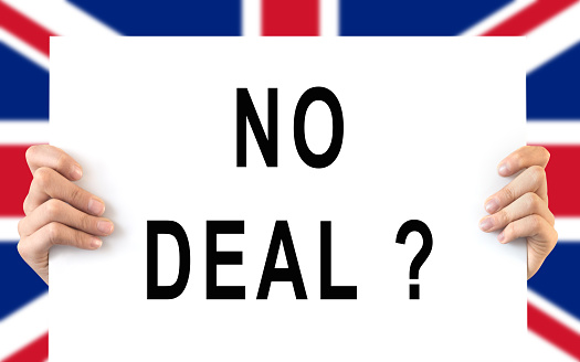 Hands holding a board 'No Deal', UK flag background, brexit concept