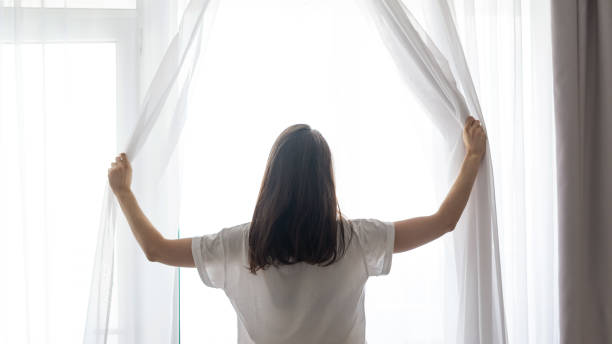 istock Woman waking up and standing near window 1175221643