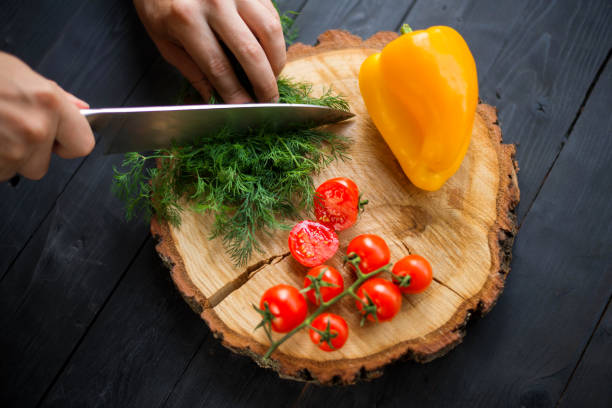 istock Chef cutting greens on a wooden board, close-up. 1175224440
