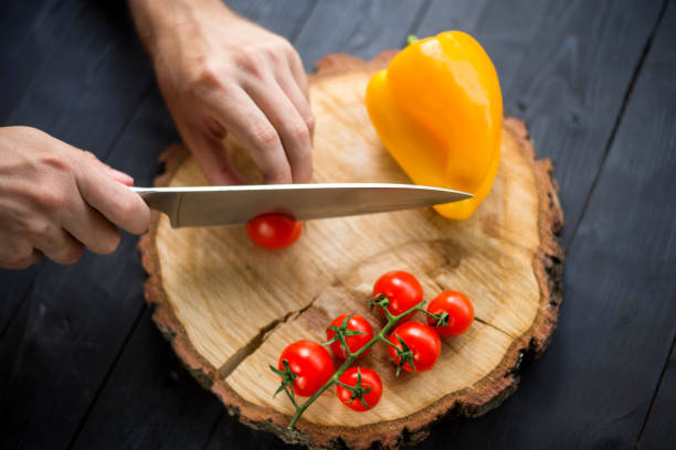 istock Chef slicing cherry tomatoes on a wooden board, close-up. 1175224478