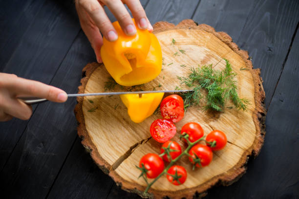 istock Chef cook cuts yellow bell pepper on a wooden board, closeup. 1175224516