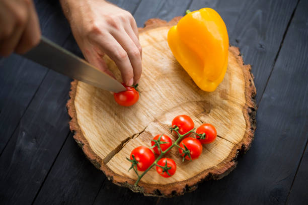 istock Chef slicing cherry tomatoes on a wooden board, close-up. 1175224538