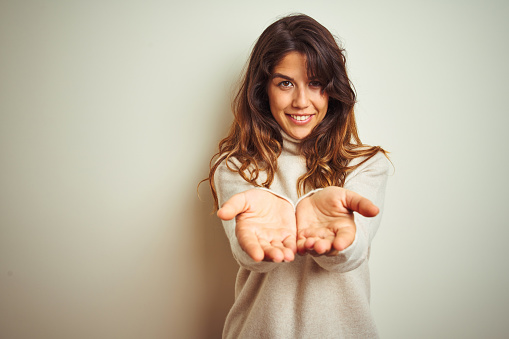 Young beautiful woman wearing winter sweater standing over white isolated background Smiling with hands palms together receiving or giving gesture. Hold and protection