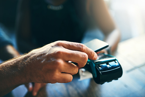 Cropped shot of an unrecognizable businessman scanning his cellphone to pay for his bill in a cafe