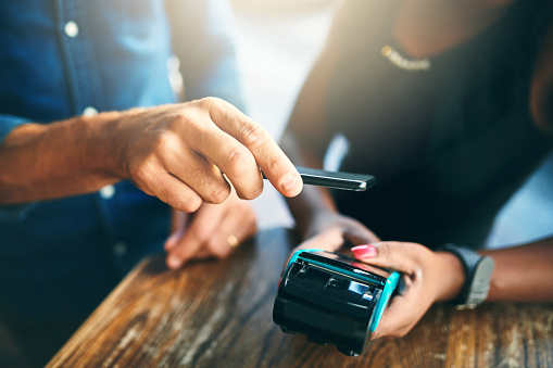 Cropped shot of an unrecognizable businessman scanning his cellphone to pay for his bill in a cafe