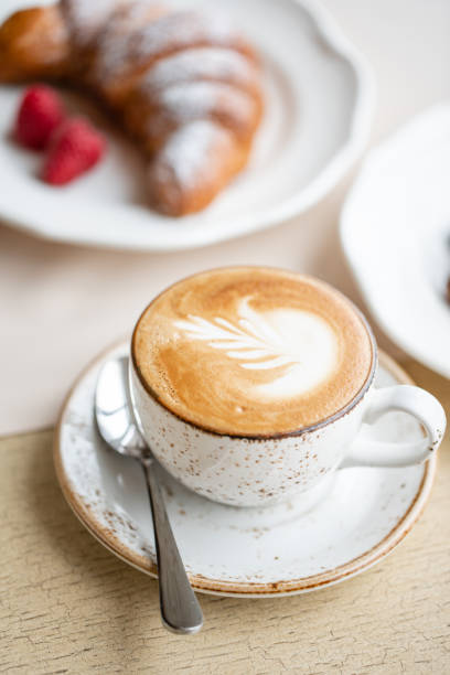 istock Coffee cappuccino with croissant on white plate in restaurant. Light morning Breakfast, fresh warm pastries and raspberries 1175226497