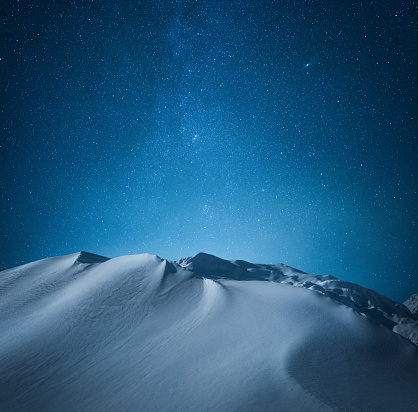Snowcapped mountains under starry night sky.