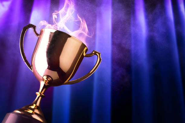 istock Winner trophy with smoke and background violet light ray on dark blue curtain. 1175229389