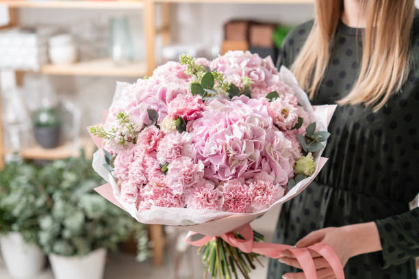 beautiful fresh cut bouquet of mixed flowers in woman hand. the work of the florist at a flower shop. delicate pastel tones color - flower head bouquet built structure carnation imagens e fotografias de stock