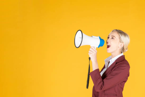 istock Business woman is announcing from megaphone on yellow background 1175236868