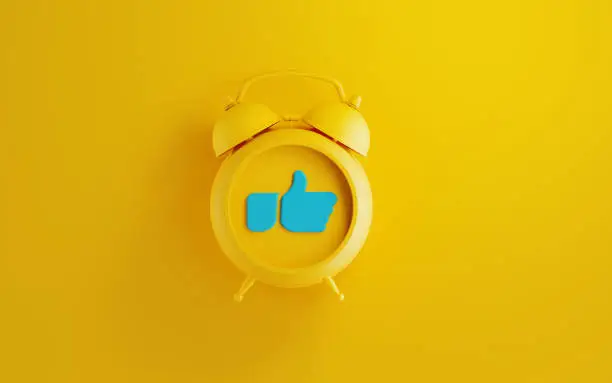 Photo of Yellow Alarm Clock with Thumbs Up Icon  on Yellow Background