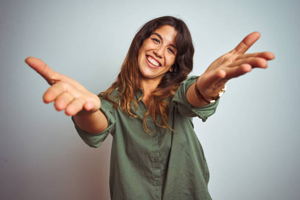 istock Young beautiful woman wearing green shirt standing over grey isolated background smiling cheerful offering hands giving assistance and acceptance. 1175238708