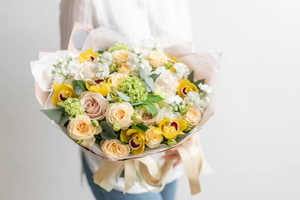 beautiful fresh cut bouquet of mixed flowers in woman hand. the work of the florist at a flower shop. delicate pastel tones color - flower head bouquet built structure carnation imagens e fotografias de stock