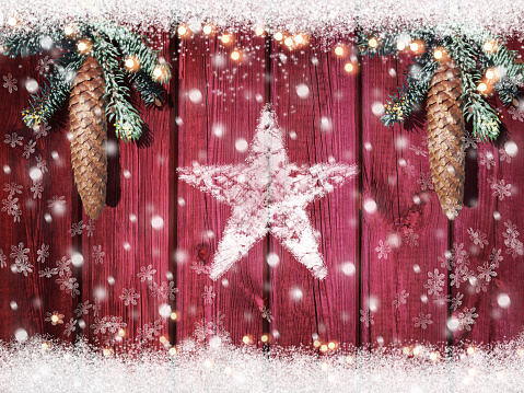 Vintage christmas decoration with fir tree branches and cones on wooden background with snow star falling snowflakes and lights