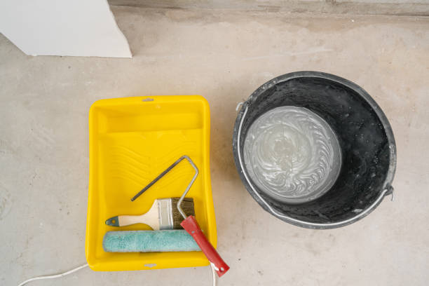 istock Paintbrush, roller and glue container on concrete surface. Composition tools for home repair and interior renovation indoors. 1175242081