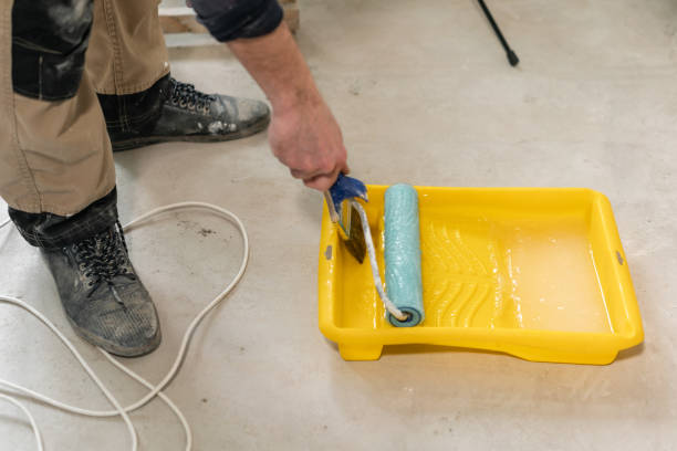 istock Young repairman smear on wall glue with a roller. . Worker glueing wallpapers on concrete wall. Repair the apartment. Home renovation concept. White Wallpaper for paint 1175243714