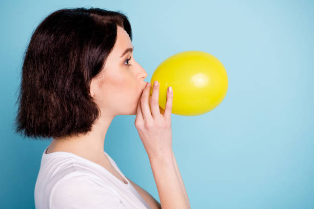 profile side view portrait of her she nice attractive lovely winsome girl blowing festive air ball isolated on bright vivid shine vibrant blue turquoise color background - inflating balloon blowing air imagens e fotografias de stock