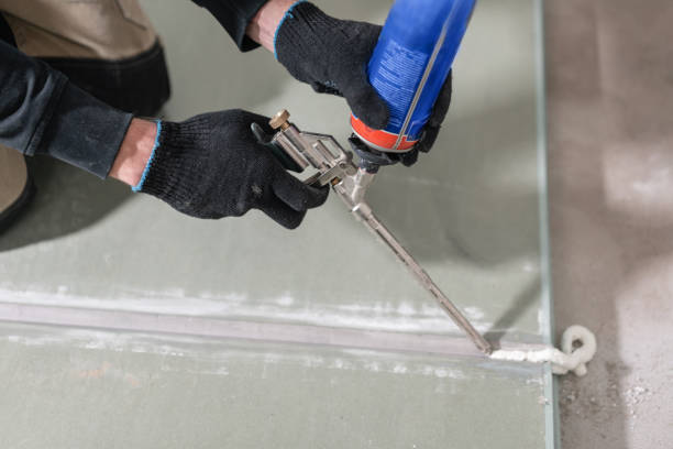 istock Worker is using a polyurethane foam for gluing drywall at ninety degrees. Hand holding polyurethane expanding foam glue gun applicator 1175245582