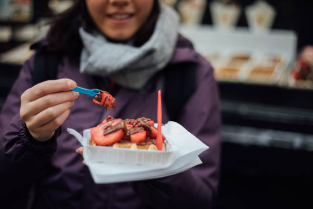 frau mit belgischen waffel im freien - brussels waffle belgian waffle people stock-fotos und bilder